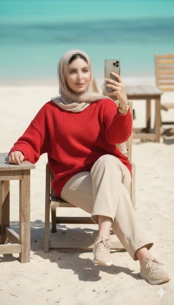 Woman in red sweater taking selfie on sandy beach with turquoise sea background