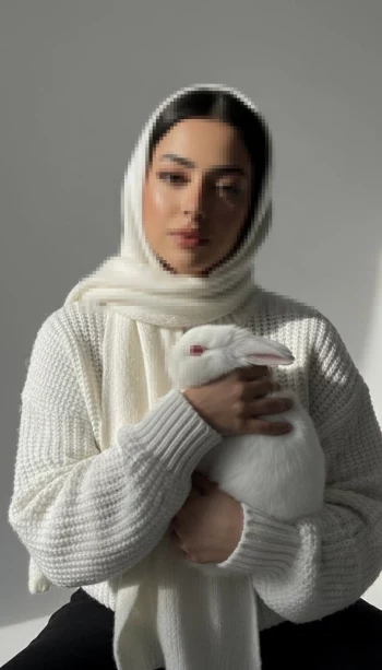 Woman in white hijab holding a white rabbit under soft natural light