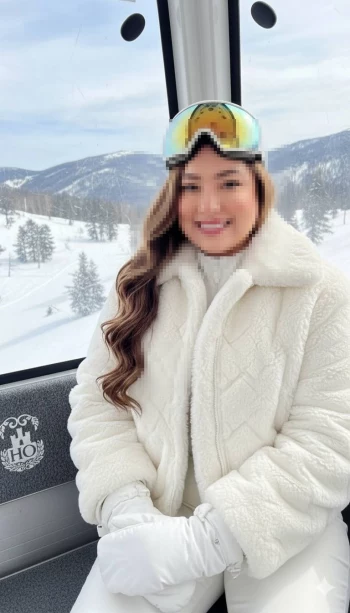 Woman in white winter outfit enjoying snowy mountain view in a cable car