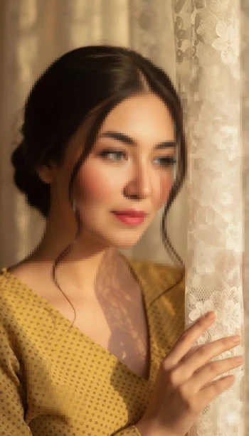 Woman in yellow dress standing by lace curtain in warm sunlight