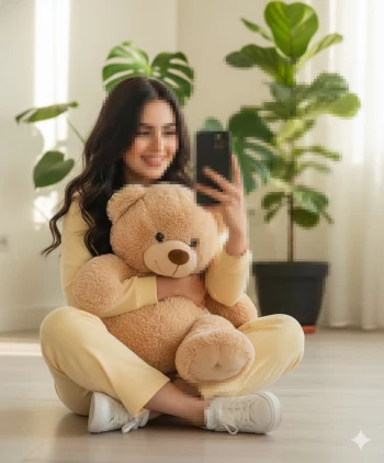 Woman in yellow outfit taking a selfie while hugging a teddy bear at home
