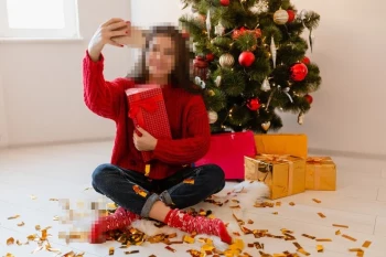 Woman Taking a Festive Selfie with Christmas Gifts Beside Holiday Tree